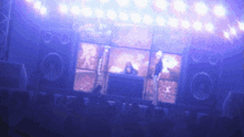 a group of people are standing in front of a stage with a dj on it
