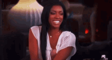 a woman in a white shirt is smiling while sitting on a chair .