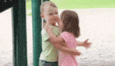 a little boy and a little girl are hugging each other in a park .