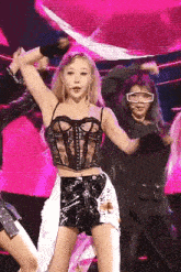 a woman in a corset is dancing on a stage in front of a pink background .