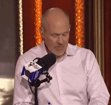 a man in a white shirt stands in front of a microphone with a sticker that says ' fox news ' on it