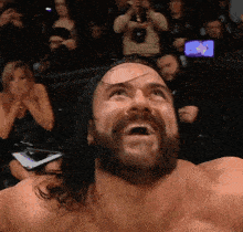 a man with a beard is screaming in front of a crowd of people