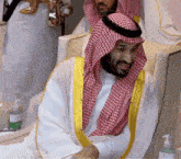 a man with a beard wearing a white robe and a red and white checkered scarf