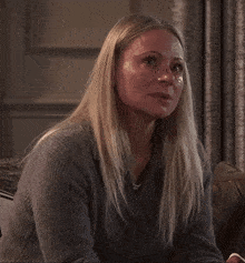 a woman in a grey sweater is crying