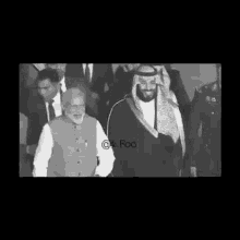 a black and white photo of a man in a keffiyeh walking with a man in a suit .