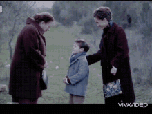 two women and a boy are standing in a field with the word vivavideo on the bottom right