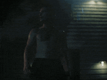a shirtless man in a dark room with stairs in the background
