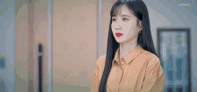 a woman with long black hair is wearing a yellow shirt