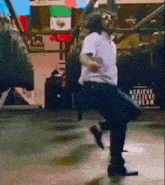 a man is dancing in front of a sign that says achieve believe dream .