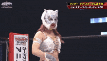 a female wrestler wearing a mask and gloves stands in front of a screen that says #stardom