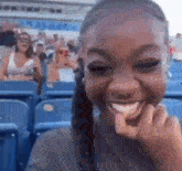 a woman is sitting in a stadium with her hand on her face and smiling .