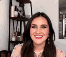 a woman is smiling and looking at the camera in front of a shelf .