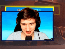 a man wearing headphones and a microphone in front of a screen that says " m "