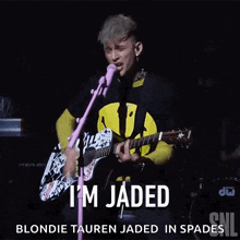 a man singing into a microphone while playing a guitar and the words i 'm jaded blonde tauren jaded