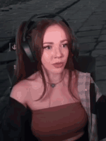 a woman is wearing headphones and a crop top while sitting in a chair .