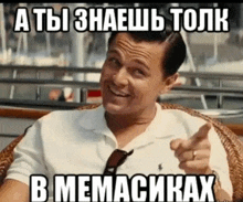 a man is sitting in a chair and pointing at the camera with a meme written in russian .