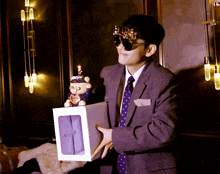 a man in a suit and tie is holding a box with a stuffed animal inside of it