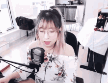 a woman wearing glasses is sitting in front of a microphone in a living room .