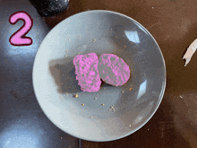 a plate with two pink pieces of food on it and the number 2 below it