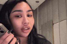 a woman with long black nails is talking on her phone