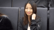 a woman in a black jacket is sitting in a dark room