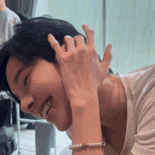 a man wearing a pearl bracelet with a cross on it is smiling