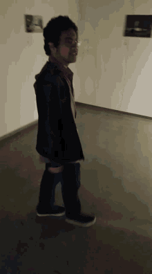 a man walking in a dark room with pictures on the wall