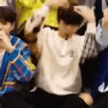 a group of young people are sitting on the floor with their arms in the air and their hands in the air .