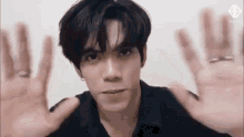 a young man in a black shirt is making a face with his hands outstretched .