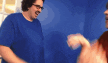a man wearing glasses and a blue shirt is laughing