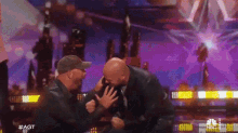 two men are fighting on a stage in front of a purple background and the words #agt on the bottom