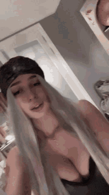 a woman with long blonde hair is wearing a hat and a black top
