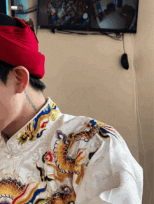 a man wearing a white shirt with a dragon embroidered on the collar