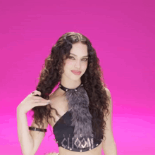 a woman with long curly hair is wearing a choom crop top