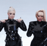 two women in black latex outfits with the letter e on their chests