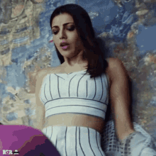 a woman in a white crop top and striped shorts is laying on the floor .