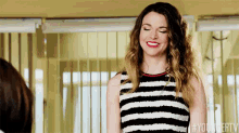 a woman in a black and white striped dress is smiling