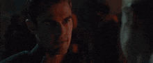 a close up of a man 's face in a dark room looking at another man .