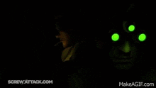 a person wearing a helmet with green eyes and a red light in the background .