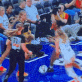 a basketball game is being played in front of a crowd and the number 77 is on the back of a player 's jersey
