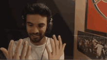 a man wearing headphones has his hands up in front of a picture of a soccer team