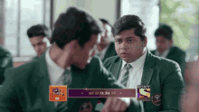 a boy in a green suit and tie is talking to another boy in a classroom with a sony advertisement on the bottom