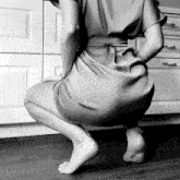 a black and white photo of a woman squatting on the floor