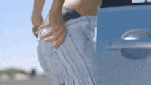 a woman is taking off her green bikini bottoms on the beach