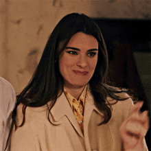 a woman in a white coat and yellow polka dot shirt smiles