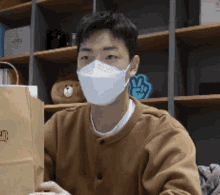 a man wearing a face mask is holding a brown bag that says vlive on it