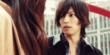 a man and a woman are looking at each other and the man is wearing a cross necklace .