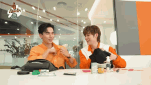 two men are sitting at a table with a balenciaga bag in front of them .