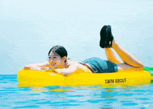 a woman in a bikini is laying on an inflatable raft that says swim about