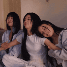 three women are sitting on a couch and one is sleeping